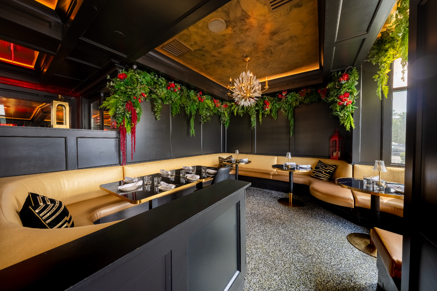 Leather booths beneath cascading greenery and a gold chandelier