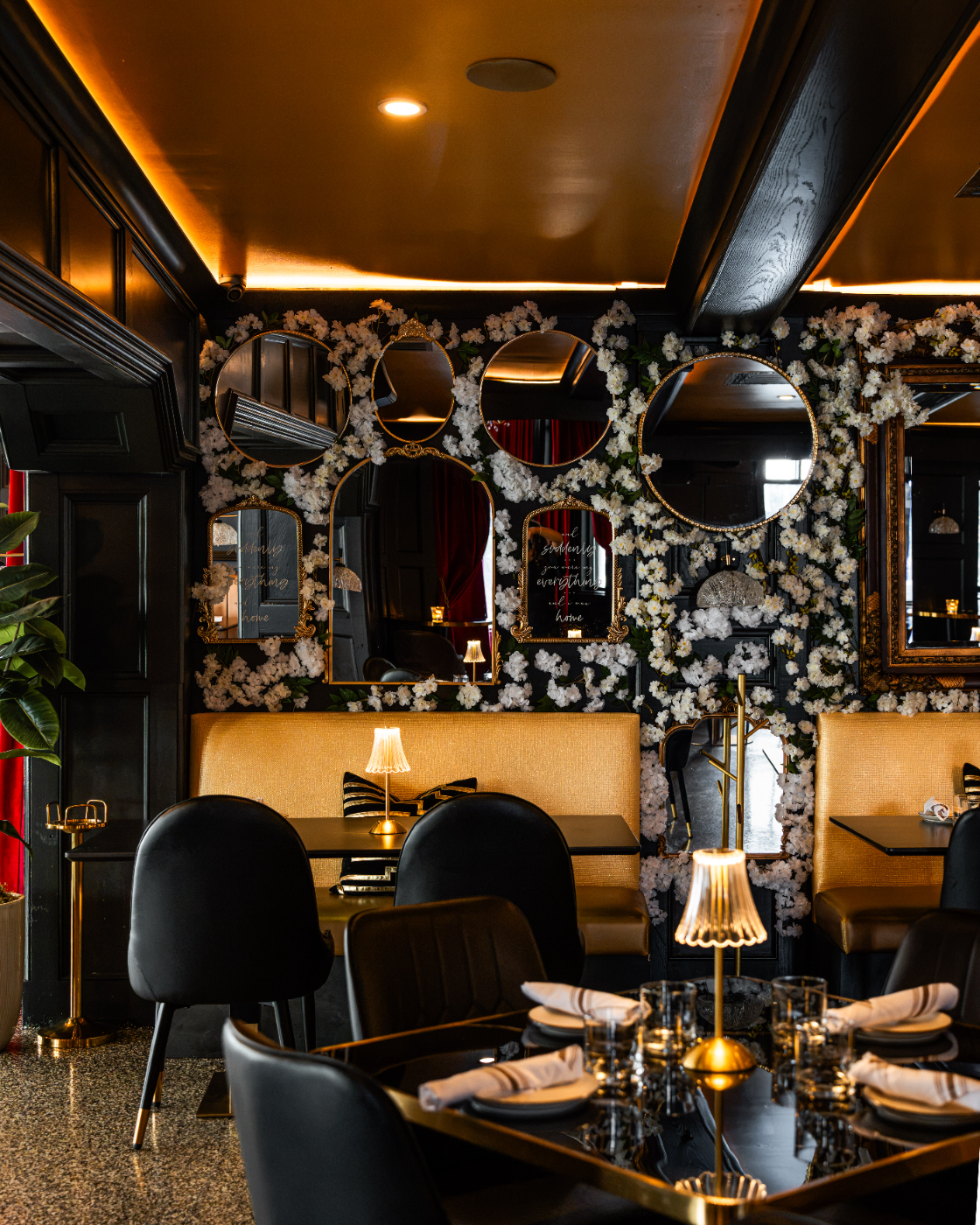 An intimate mirrored table set beneath winter greenery