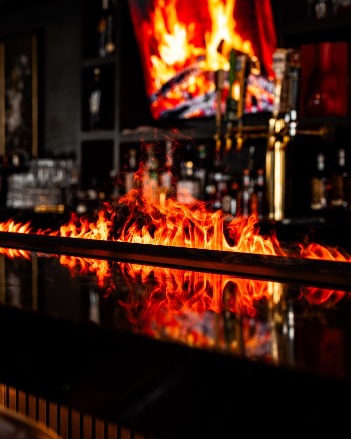 Bottles lined along the bar over dancing flames