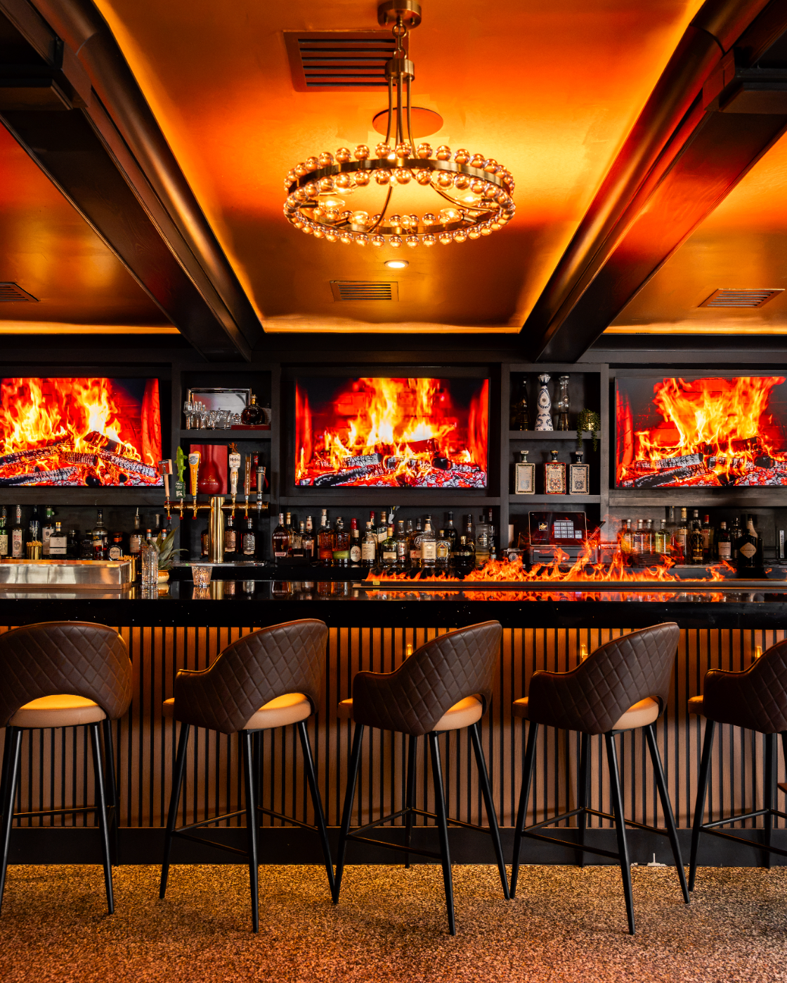 Bar seating in front of the roaring fireplace displays