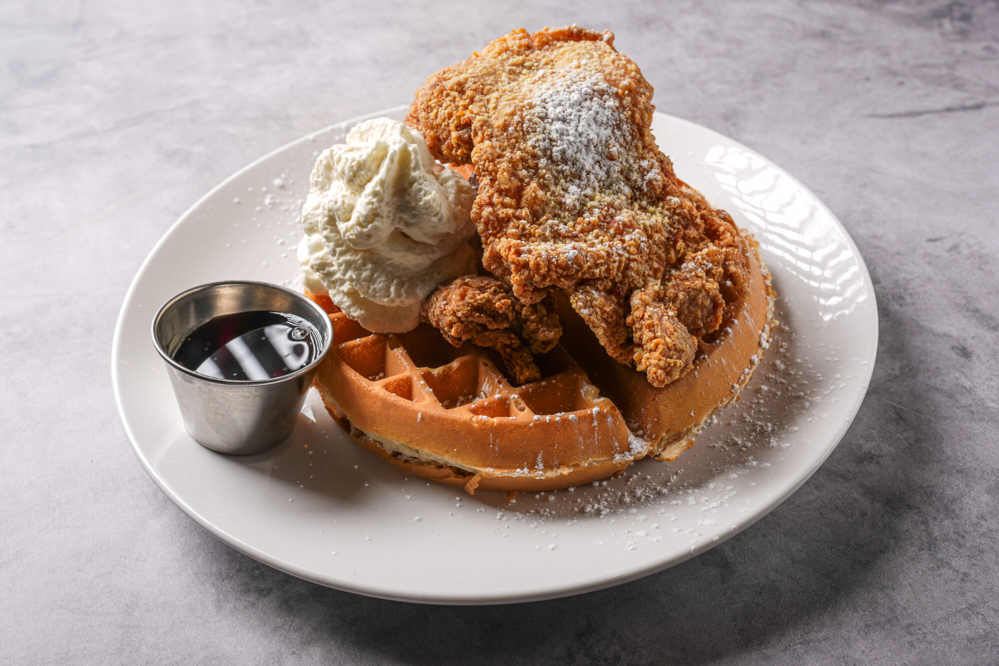 Fuego chicken & waffles dusted with powdered sugar and drizzled with maple syrup