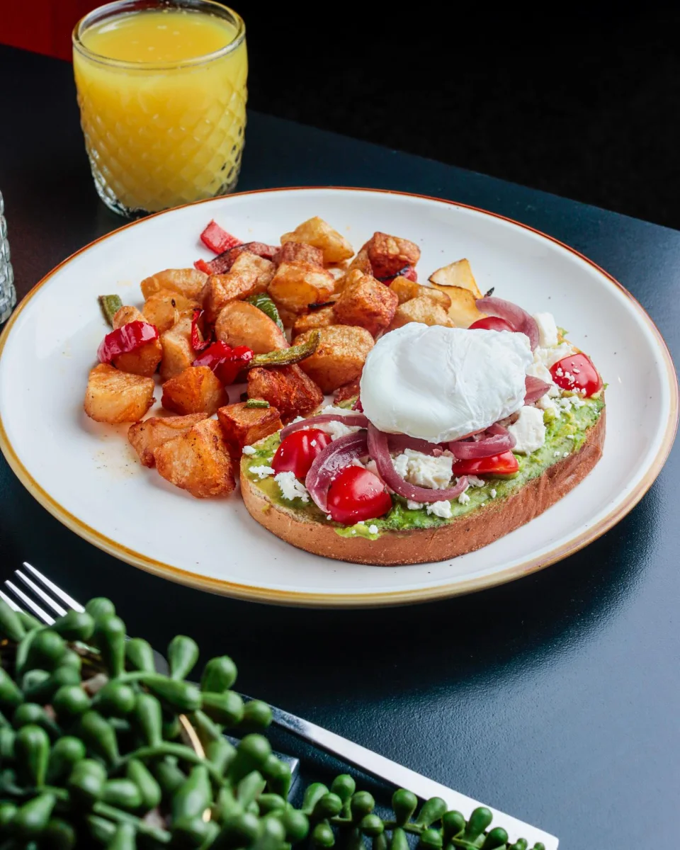 Avocado toast with poached egg, feta and home fries with fresh orange juice